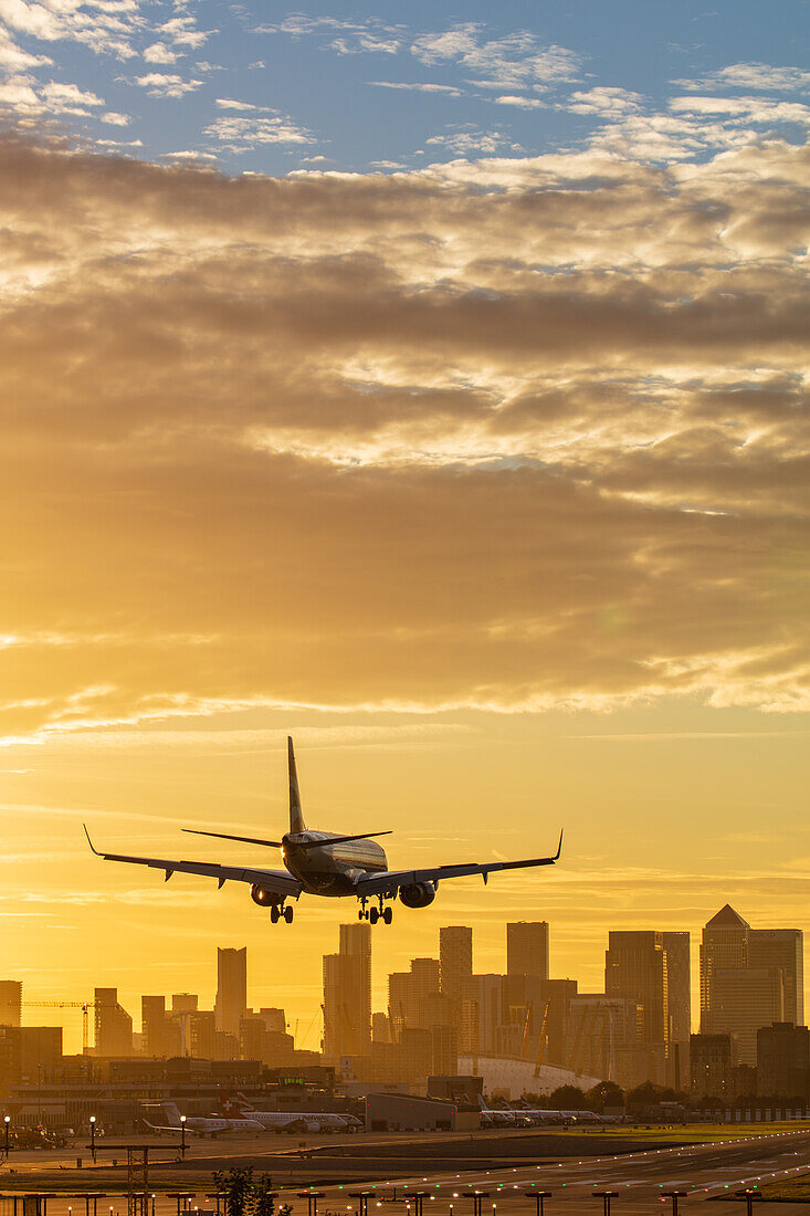 Flugzeug landet auf dem London City Airport bei Sonnenuntergang, mit Canary Wharf und O2 Arena im Hintergrund, London, England, Vereinigtes Königreich, Europa