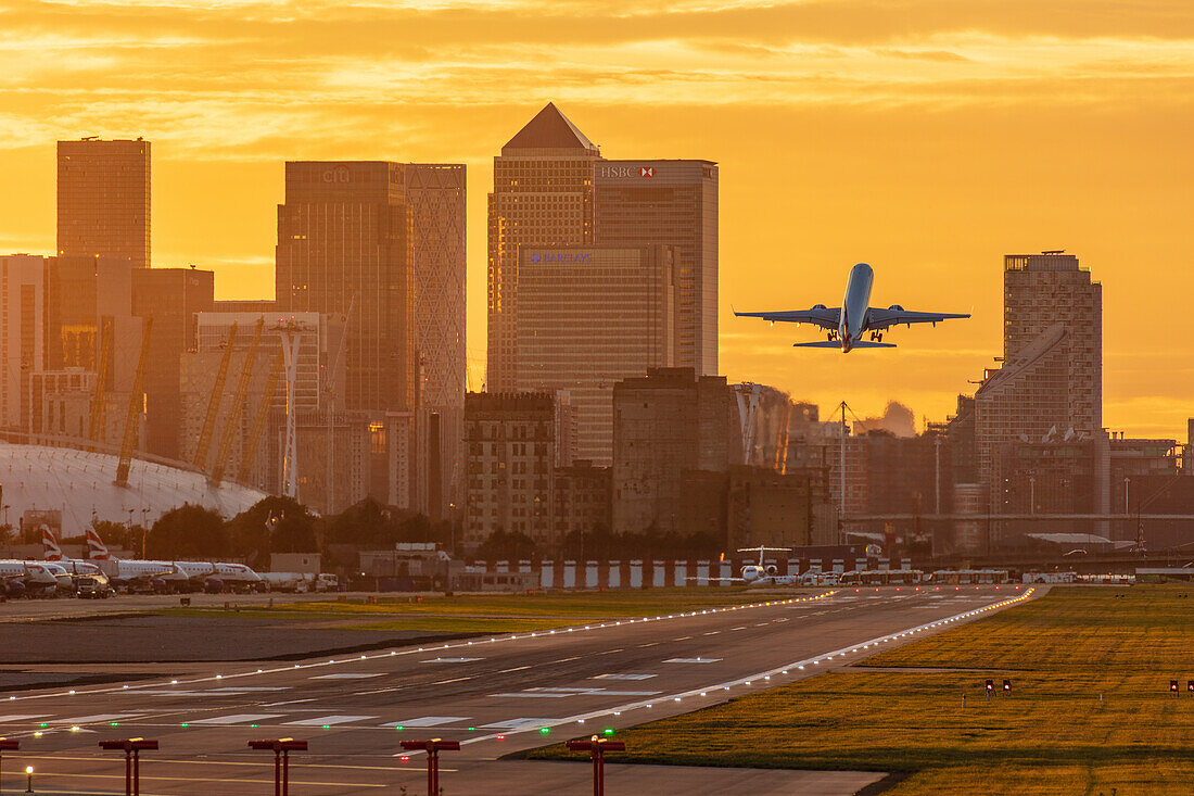 Flugzeug vom Flughafen London City bei Sonnenuntergang, mit Canary Wharf und O2 Arena im Hintergrund, London, England, Vereinigtes Königreich, Europa