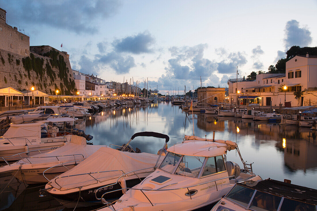 Blick vom Kai über den Hafen in der Abenddämmerung, Lichter spiegeln sich in ruhigem Wasser, Ciutadella (Ciudadela), Menorca, Balearen, Spanien, Mittelmeer, Europa