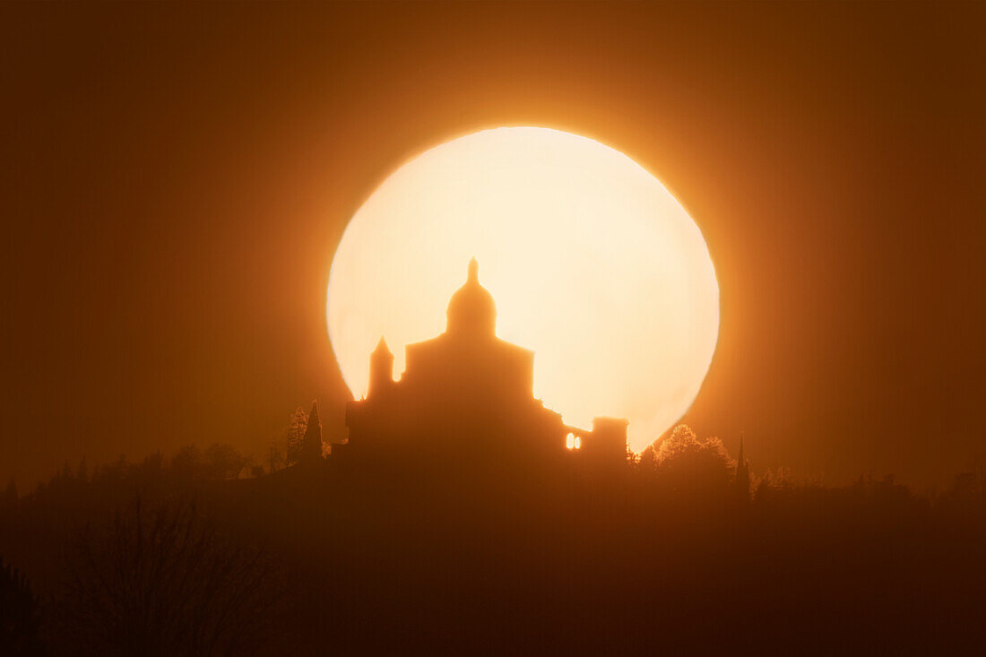 Sonne hinter der Silhouette von San Luca Sanctuary bei Sonnenuntergang, Bologna, Emilia Romagna, Italien, Europa