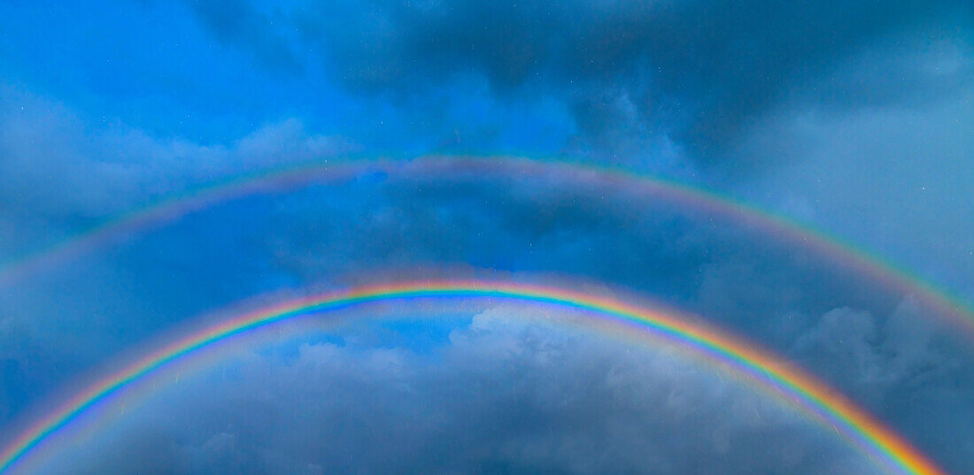 Doppelter Regenbogen gegen stürmischen Himmel