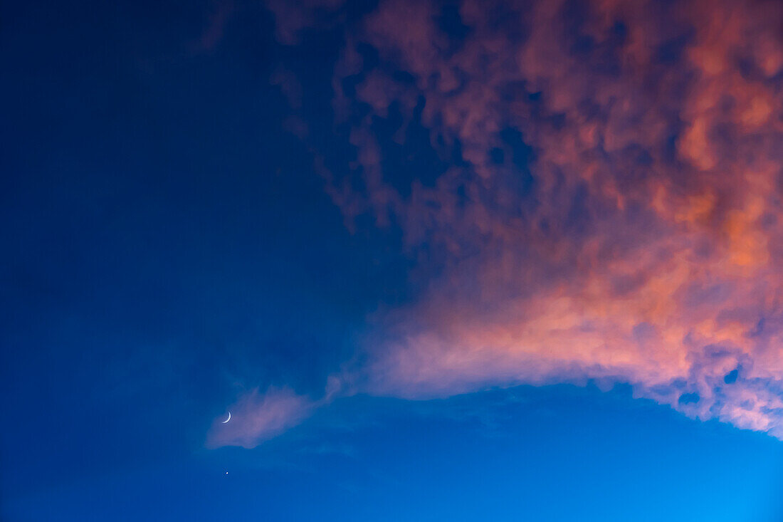 Halbmond gegen blauen Himmel mit rosa Wolken