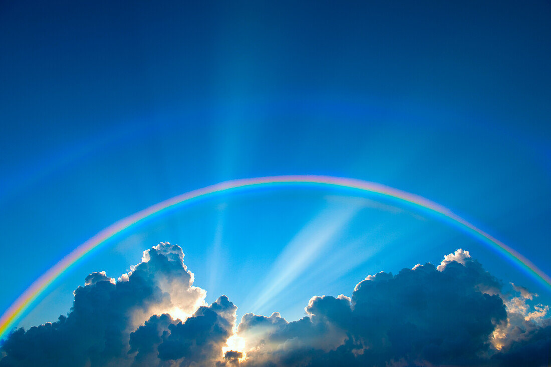 Doppelter Regenbogen und Wolken am Himmel bei Sonnenuntergang