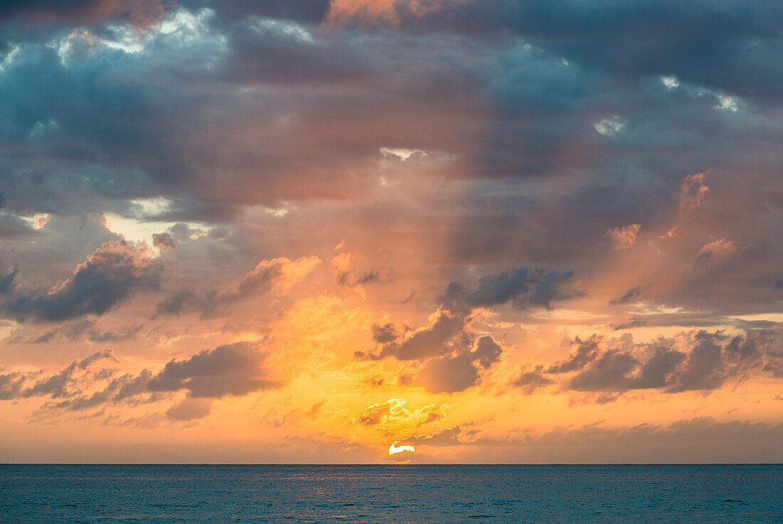 Dramatischer Himmel bei Sonnenuntergang über dem Meer