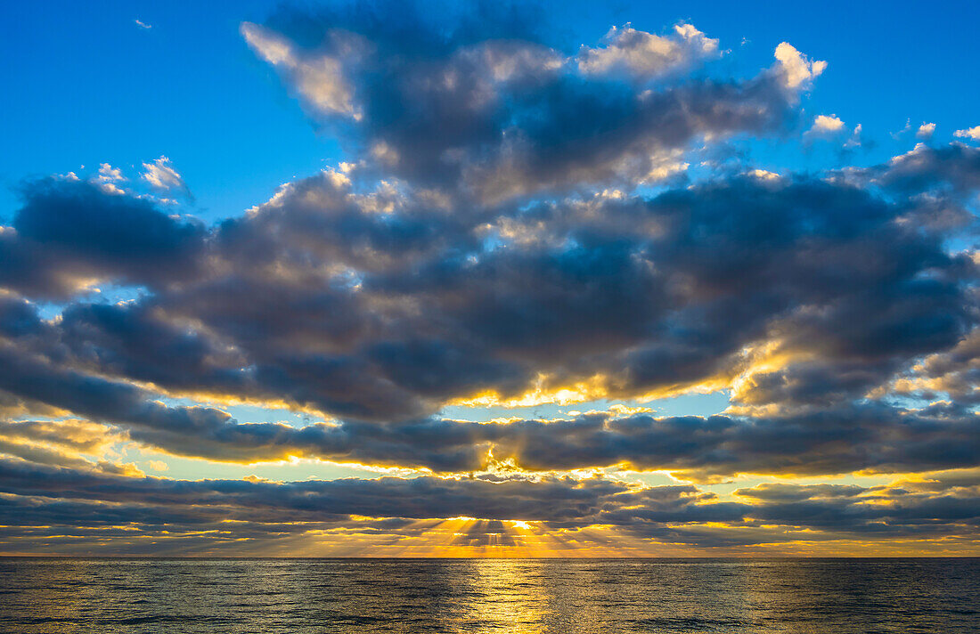 Dramatischer Himmel bei Sonnenaufgang über dem Ozean