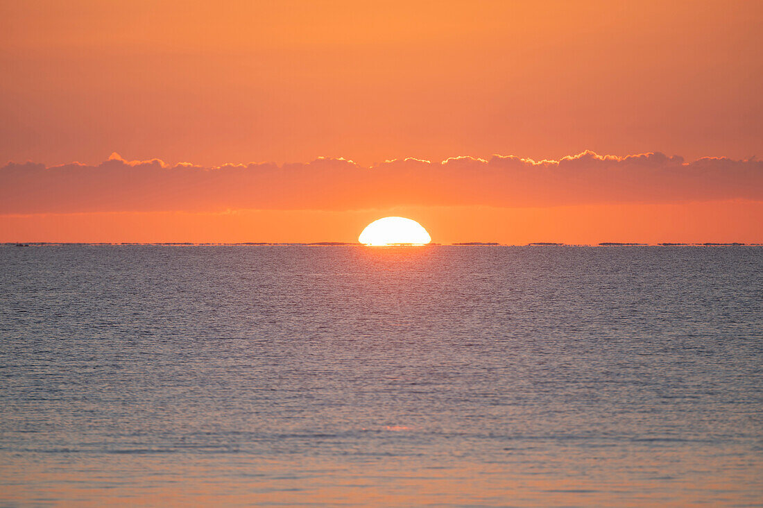 Sun rising above calm sea