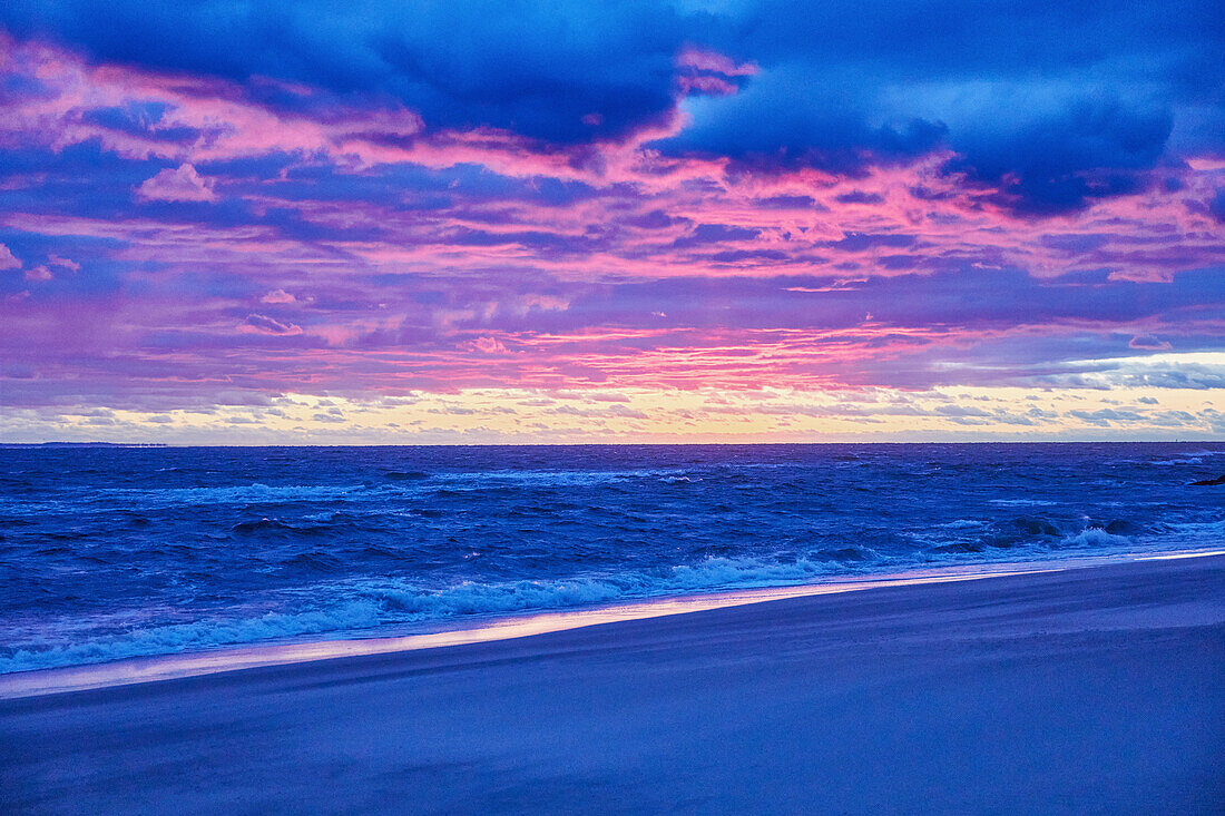 Strand und Meer bei Sonnenuntergang mit dramatischem blauen und violetten Himmel