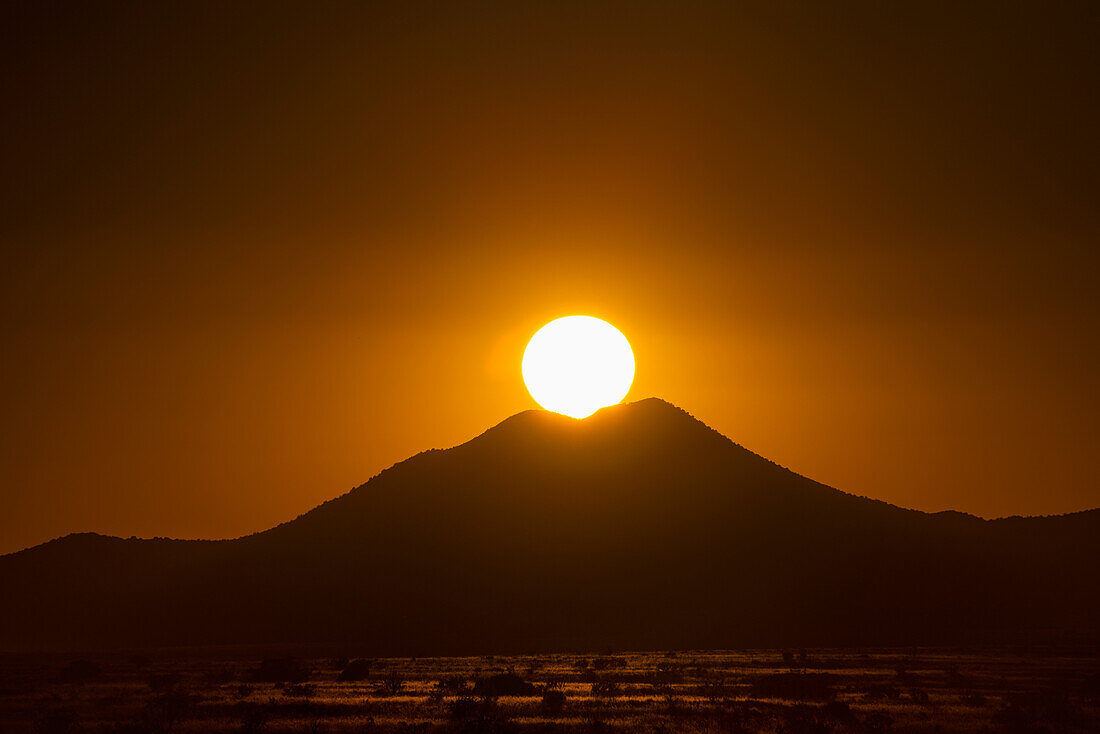 USA, New Mexico, Santa Fe, Sun setting above hill in Cerrillos Hills State Park