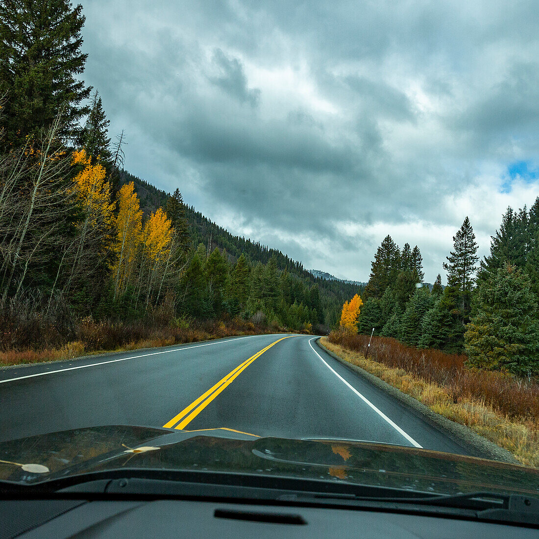 USA, Idaho, Ketchum, Autobahn in Berglandschaft im Herbst vom Auto aus gesehen