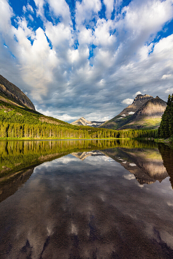 Mountains reflect into Fishercap Lake in Glacier National Park, Montana, USA.