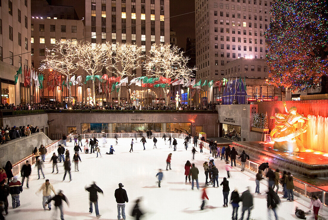 New York, NY, USA - Menschen, die auf der Eislaufbahn im Rockefeller Center Schlittschuh laufen. Über der Eisbahn stehen Bäume mit Weihnachtsbeleuchtung. (Nur zur redaktionellen Verwendung)
