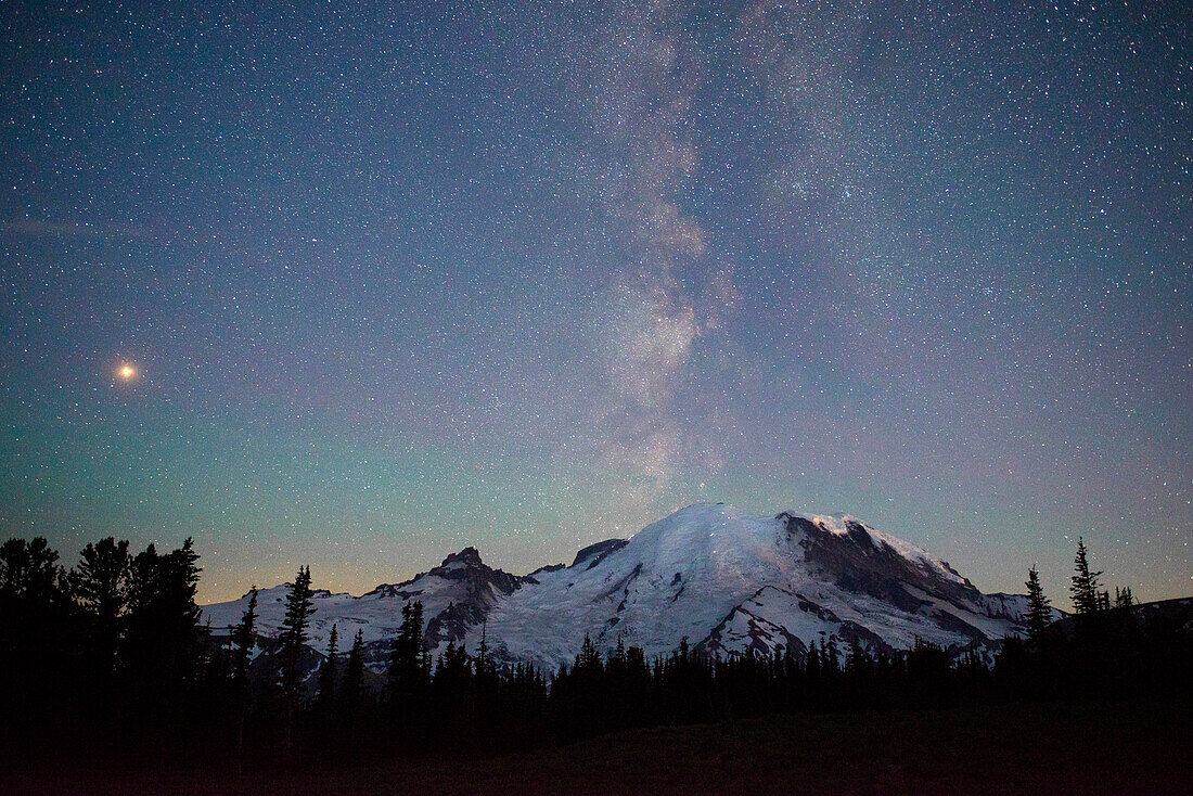 Die Lichter der Kletterer sind auf dem Berg zu sehen, wenn die Milchstraße hinter dem Mt. Rainier National Park im US-Bundesstaat Washington aufsteigt.