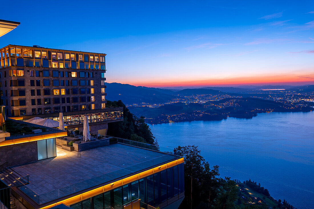 Hotel fünf Sterne Bürgenstock über dem Vierwaldstättersee und Berge in der Abenddämmerung in Bürgenstock, Nidwalden, Schweiz.