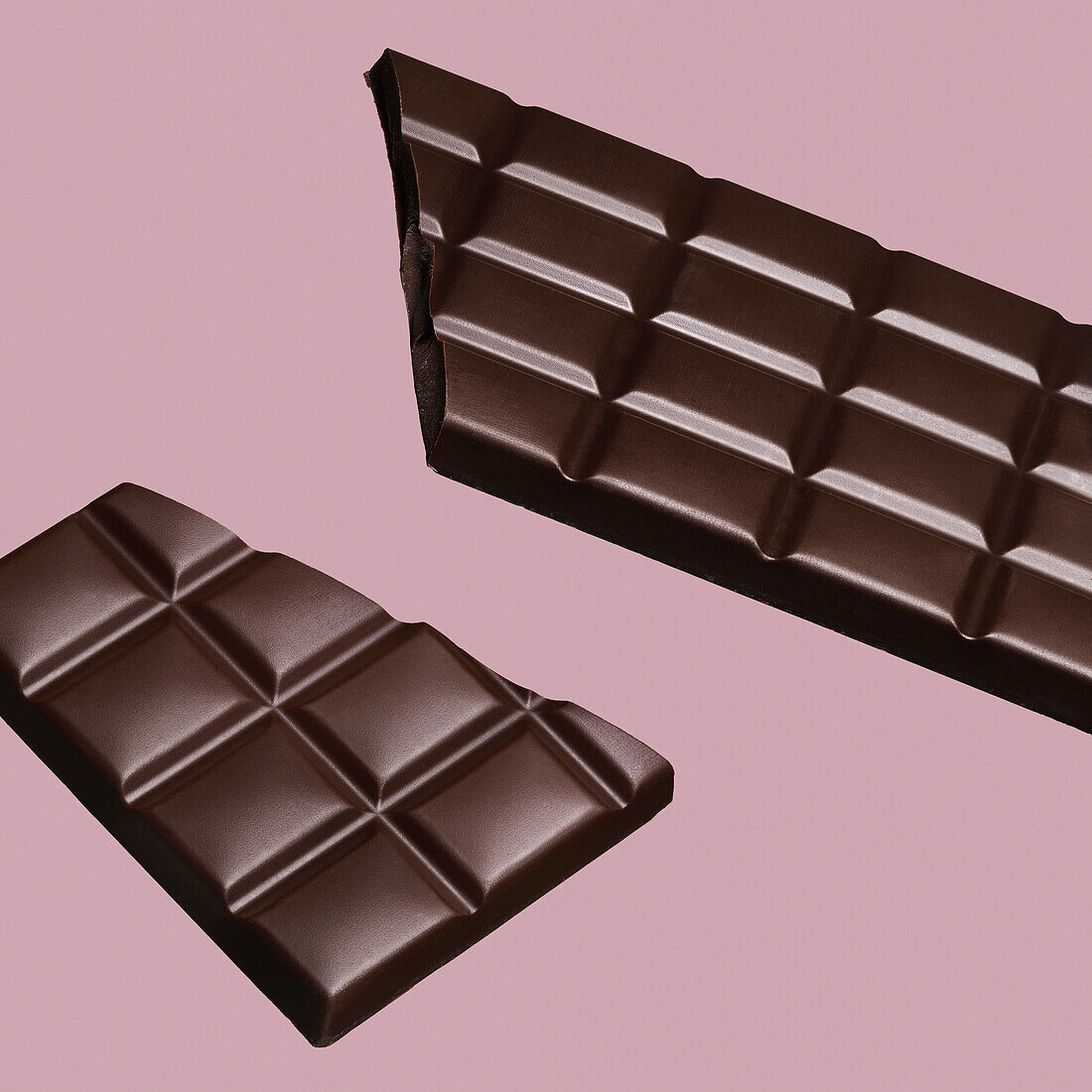 Nahaufnahme ebrochene Schokolade bar auf rosa Hintergrund