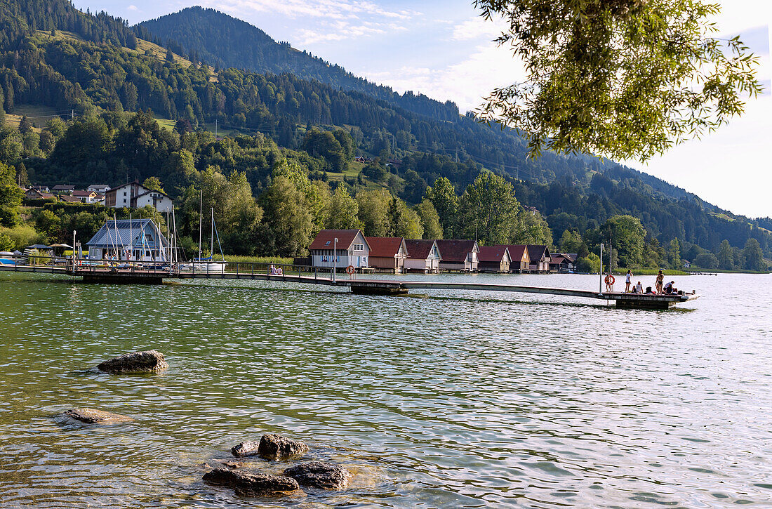Bathing jetty and boathouses at the Großer Alpsee at the Kurpark of Bühl am Alpsee in Oberallgäu in Bavaria in Germany