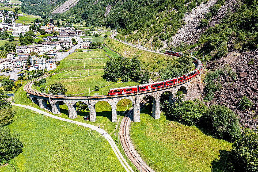 Luftaufnahme eines Zuges, der das Spiralviadukt von Brusio überquert, UNESCO-Weltkulturerbe, Rhätische Bahn, Schweiz, Europa