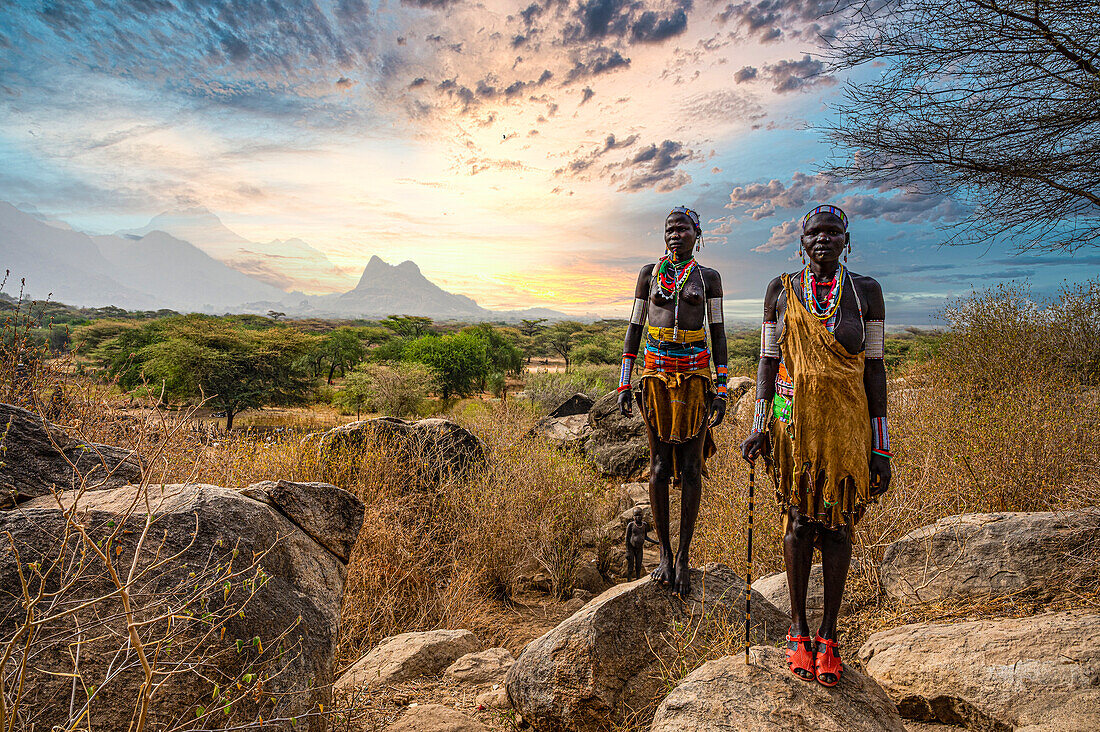 Traditional dressed young girls from the Laarim tribe standing on a rock, Boya Hills, Eastern Equatoria, South Sudan, Africa