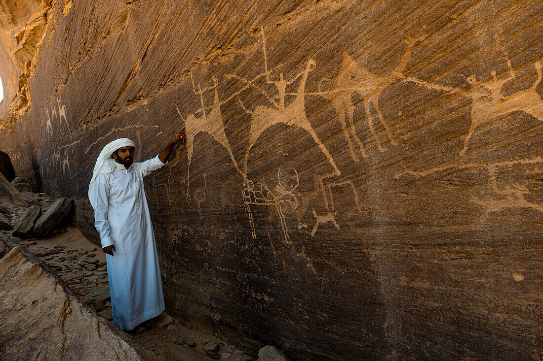 Mann zeigt auf Felszeichnungen, Felszeichnungen und Inschriften von Bir Hima, UNESCO-Weltkulturerbe, Najran, Königreich Saudi-Arabien, Naher Osten