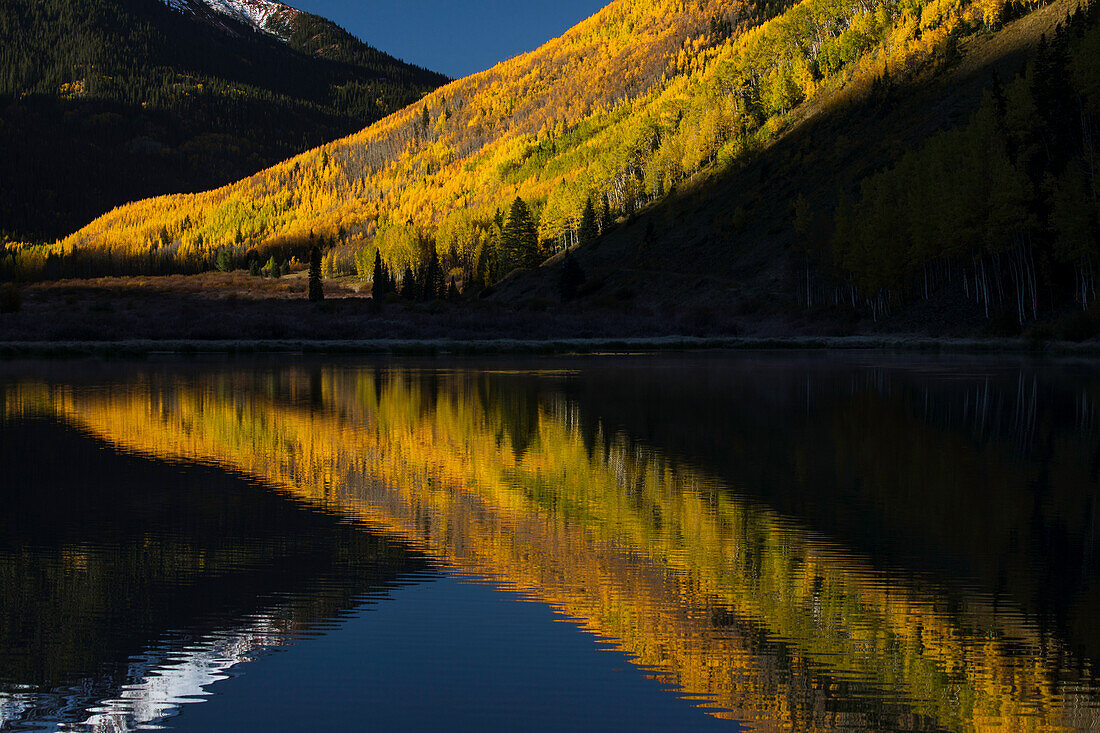 Herbstfarben und Red Mountain spiegeln sich bei Sonnenaufgang in Crystal Lake in der Nähe von Ouray, Colorado, wider