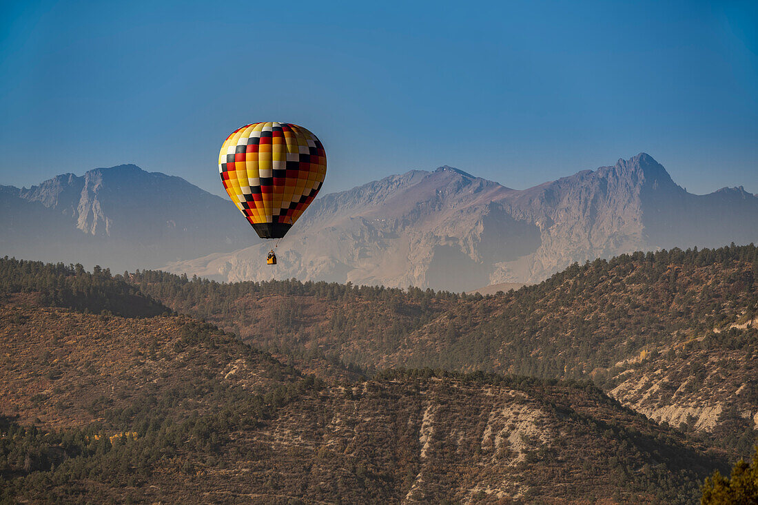 USA, Colorado, Uncompahgre National Forest. Hot air balloon floats above mountain terrain.