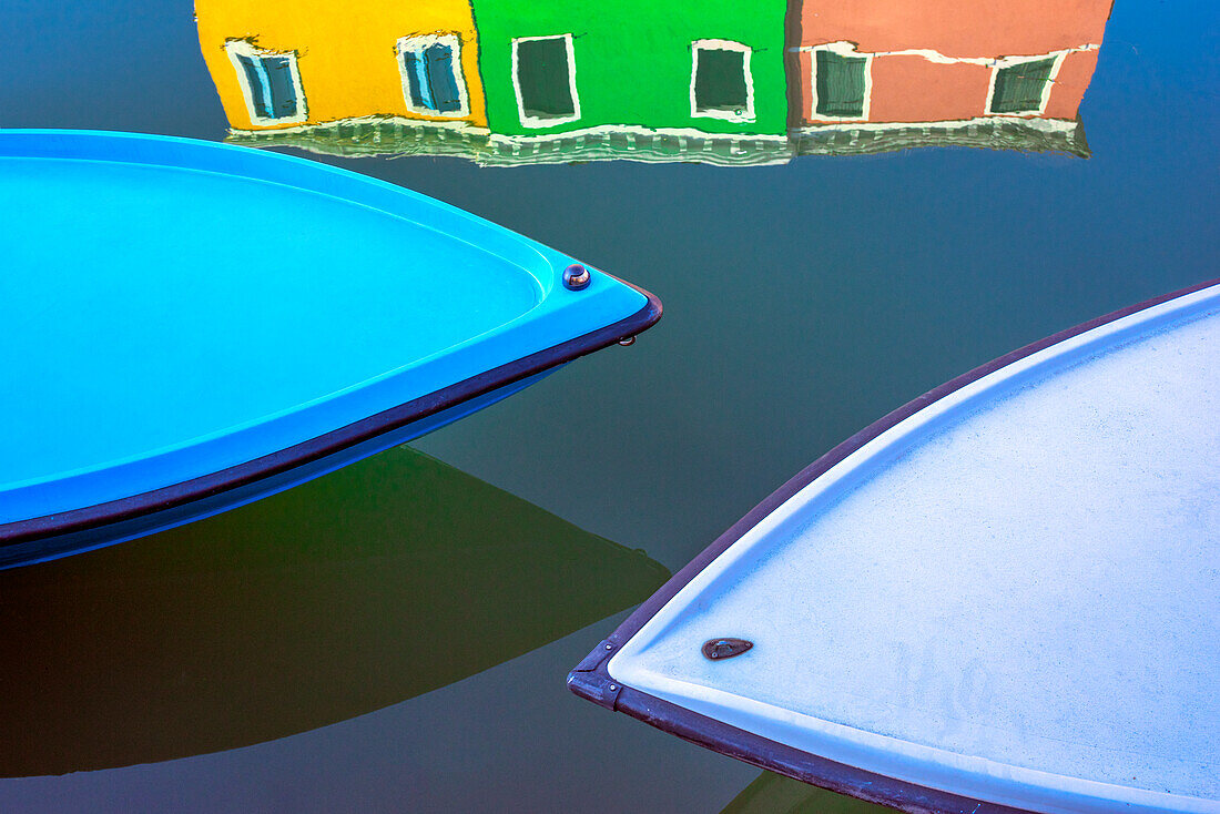 Italy, Burano. Boat bows and house reflection in canal.