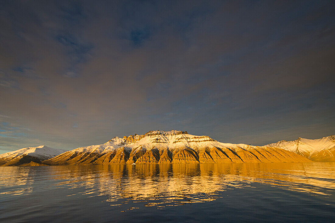 Greenland. Kong Oscar Fjord. Deeply eroded mountains reflected in the calm water.