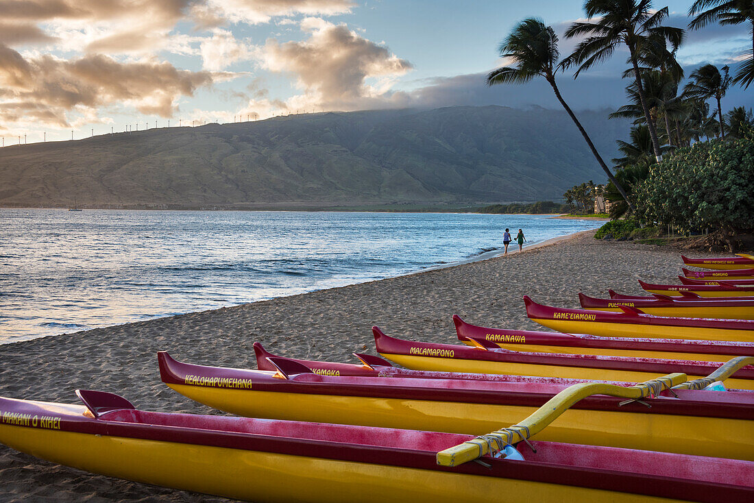 Hawaii, Maui, Kihei. Traditionelle hawaiianische Auslegerkanus im Vordergrund mit Menschen am Strand Ka Lae Pohaku und Palmen im Hintergrund.