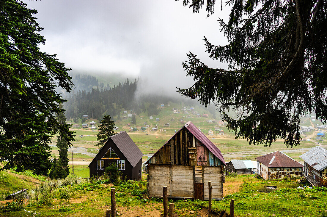 Traditional old wooden houses of Bakhmaro resort in georgian region Guria in foggy morning