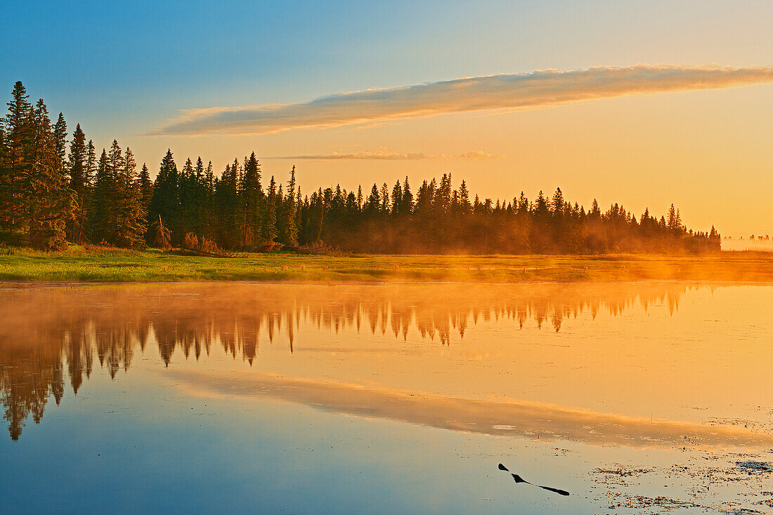 Canada, Manitoba, Riding Mountain National Park. Fog rising above Whirlpool Lake at sunrise.