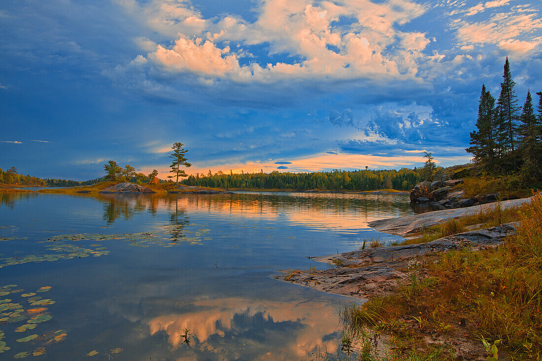 Kanada, Ontario, Distrikt Kenora. Waldherbstfarben spiegeln sich bei Sonnenaufgang auf dem Middle Lake wider