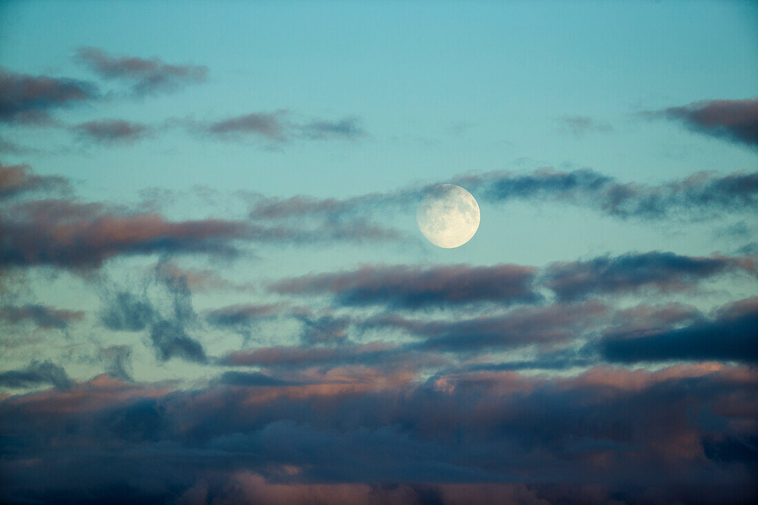 Canada, Nunavut Territory, Arviat, Full moon rises through clouds along Hudson Bay above Sentry Island