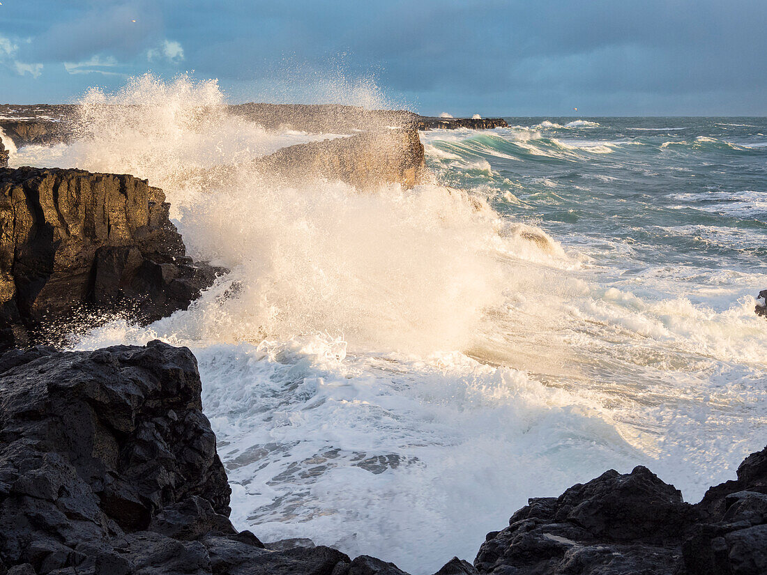 Coastline at Brimketill during winter storm conditions at sunset. Reykjanes Peninsula, Iceland.