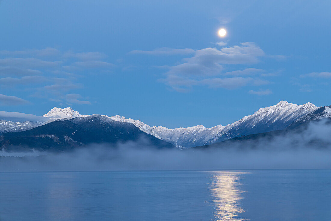 USA, Washington State, Seabeck. Moon setting over Olympic Mountains and Hood Canal.