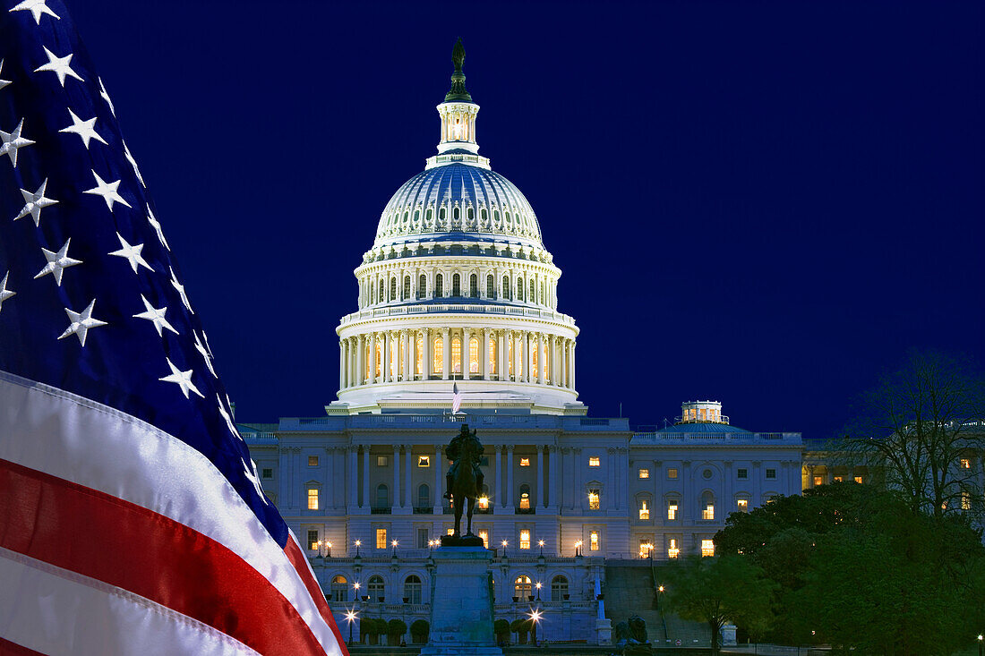 USA, Washington DC. Capitol Building and US flag at night