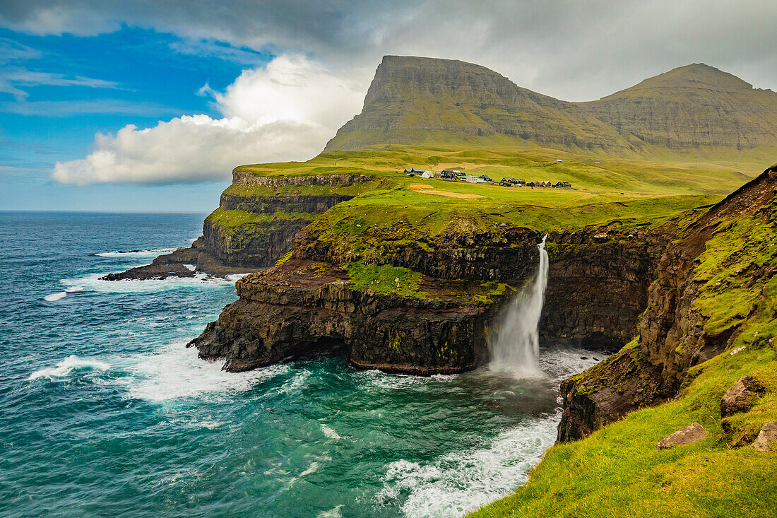 Europa, Färöer. Blick auf das Dorf Gasadalur und den Mulafossur-Wasserfall auf der Insel Vagar.