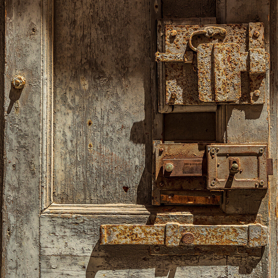 Italy, Apulia, Metropolitan City of Bari, Giovinazzo. Old wooden door with massive rusted metal locks.