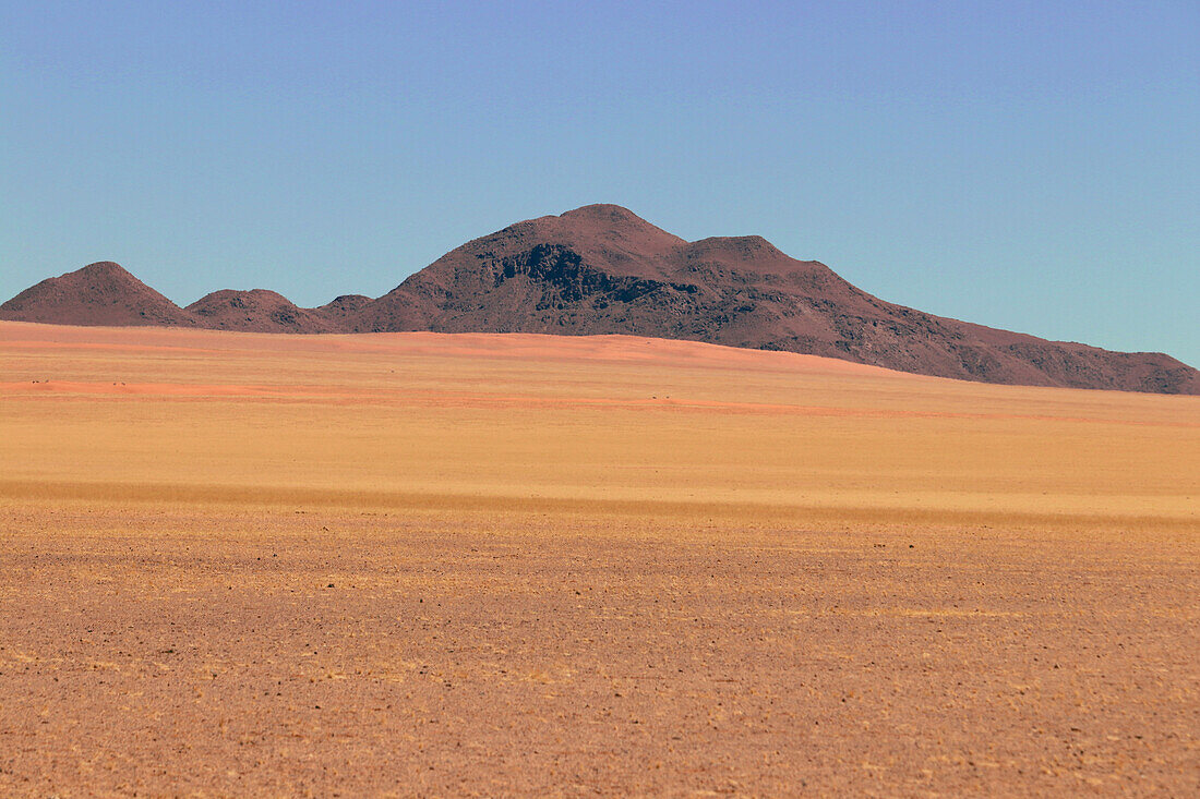 Namibia; Südnamibia; Region Hardap; Namib Wüste; gebirgige Landschaft und mit Gras bewachsene, rote Sanddünen