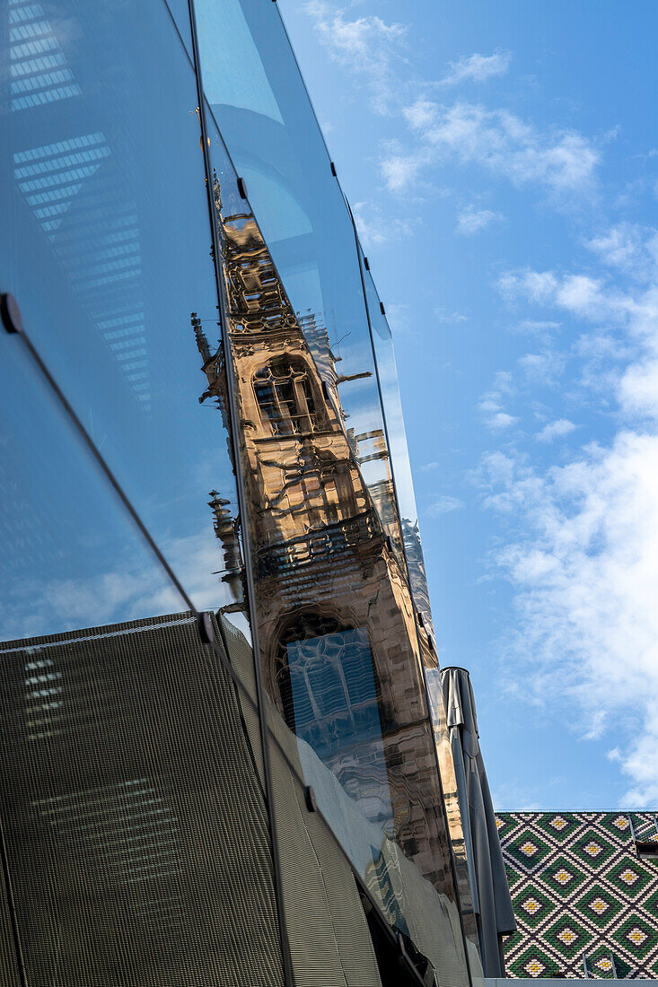 Glockenturm des Dom spiegelt sich in einem Glasgebäude wider, unter bewölktem Himmel Bozen, Südtirol, Italien