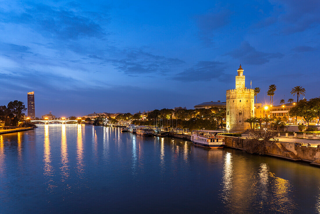 Am Ufer des Fluss Guadalquivir mit dem historischen Turm Torre del Oro in der Abenddämmerung, Sevilla, Andalusien, Spanien  