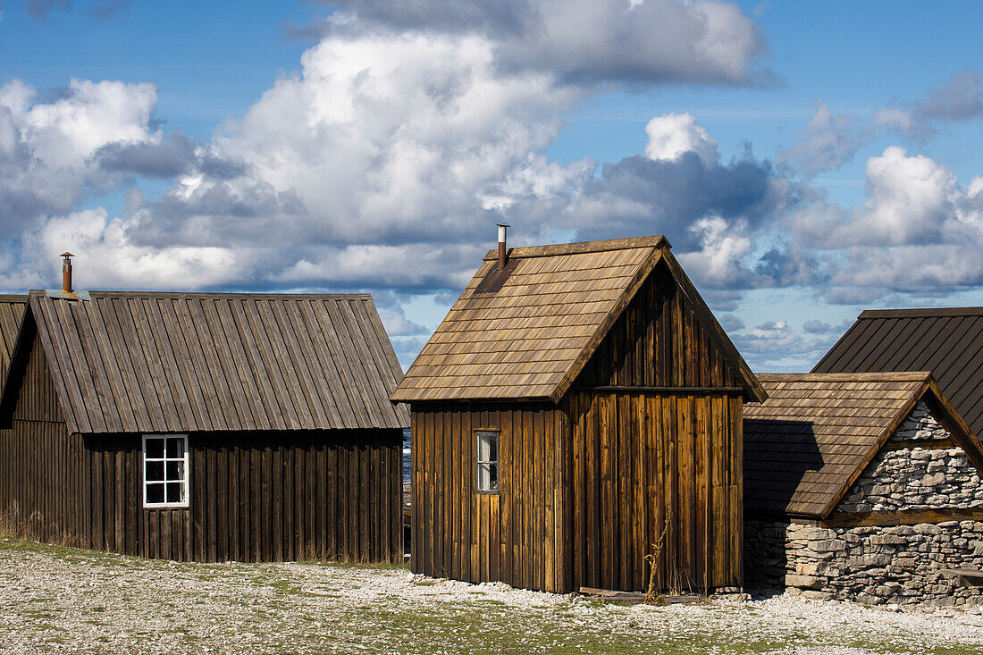 Kleine Fischerhütten stehen eng aneinander. Schäfchenwolken. Farö, Gotland, Schweden.