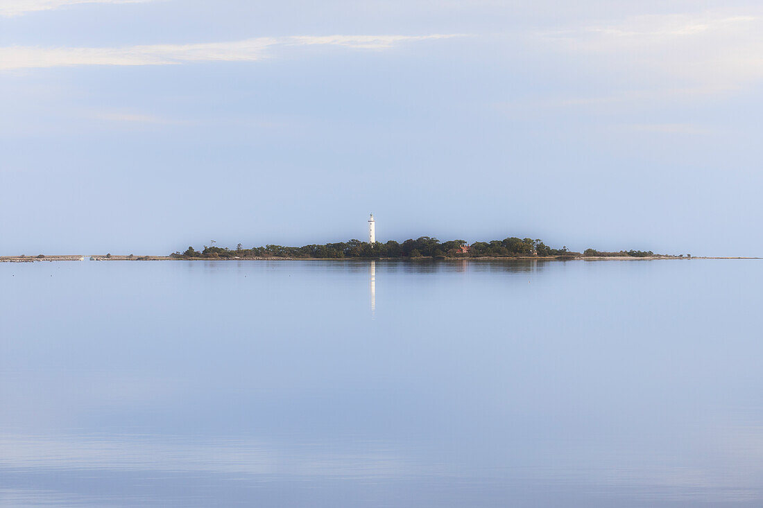 Langer Erik lighthouse from afar on the Norra Udde peninsula. reflection in the water. Oland, Sweden.