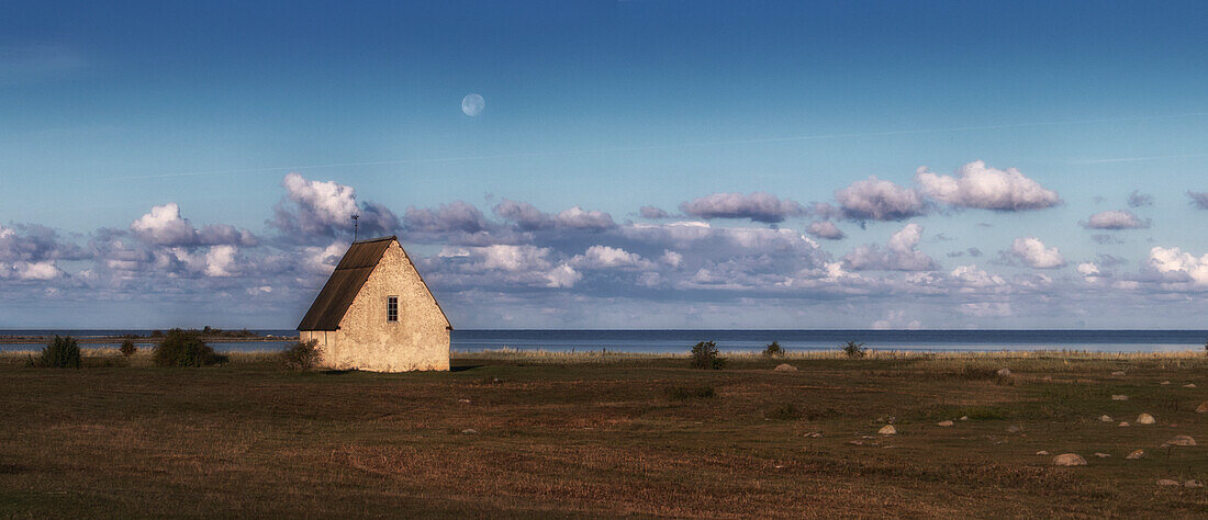 Koviks Strandkirche. Einfache Kapelle auf Weise am Meer. Mond steht über der Kirche. Klintehamn, Gotland, Schweden.