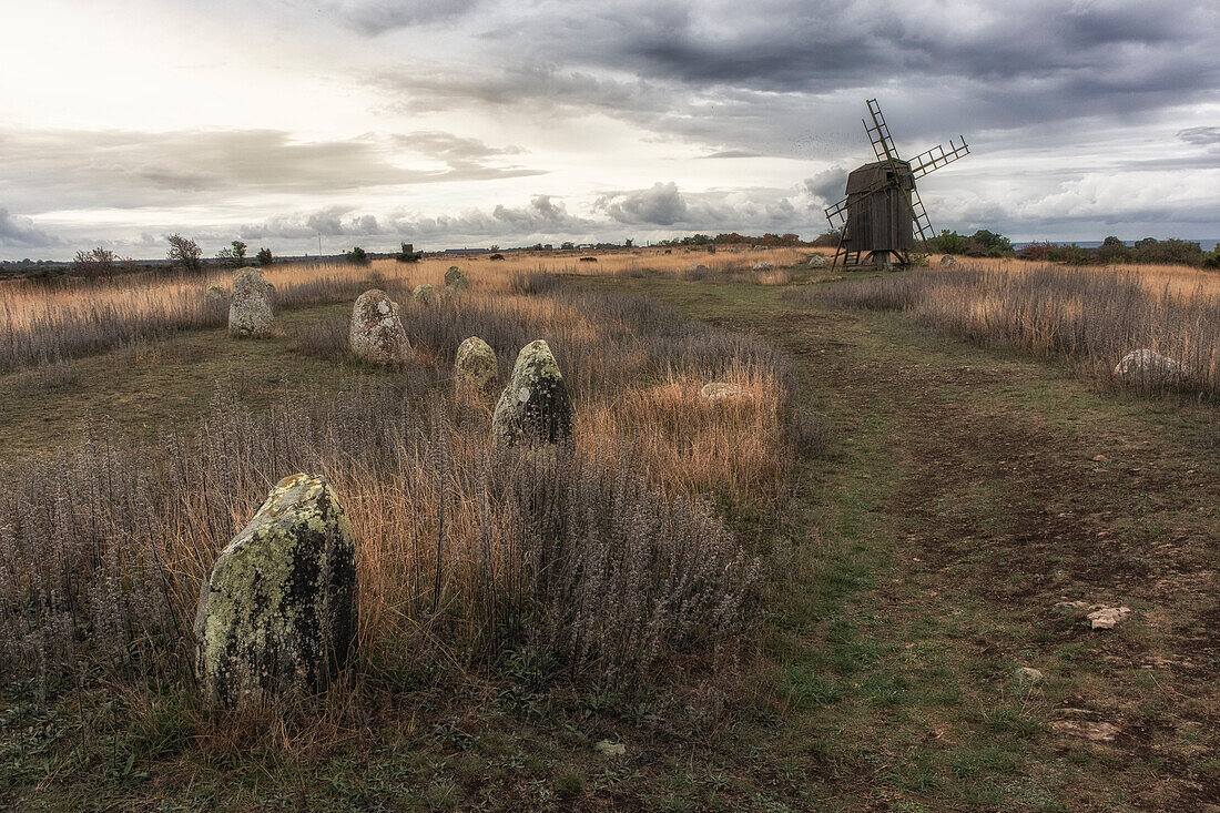 Post windmill and stone setting on Öland. Cloudy sky. path in the foreground. Oland, Sweden.