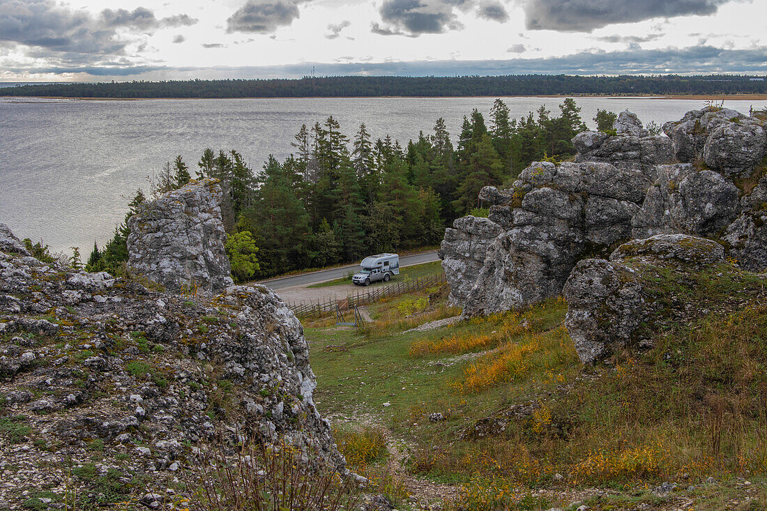 Wohnmobil steht an kleiner Straße zwischen Felsformationen. Meer im Hintergrund. Lärbro, Gotland, Schweden.