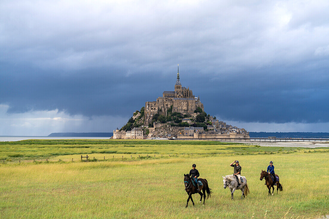 Horsemen in front of the Mont Saint-Michel monastery hill, Le Mont-Saint-Michel, Normandy, France