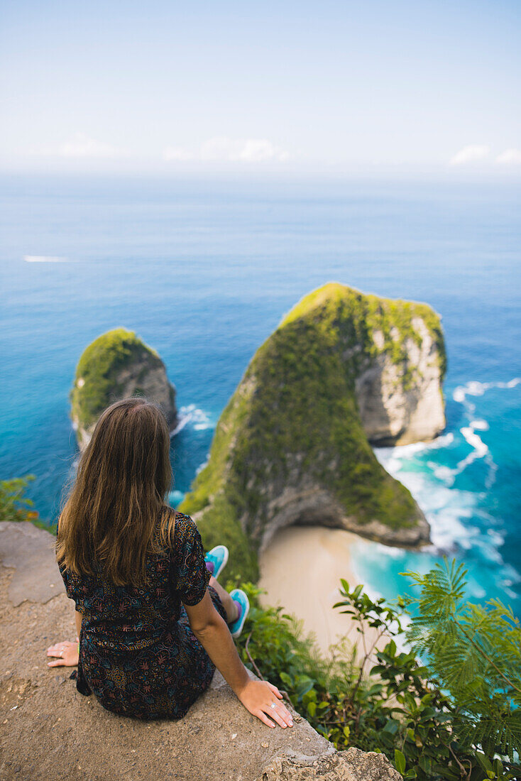 Frau sitzt über Kelingking Beach in Nusa Penida, Indonesien