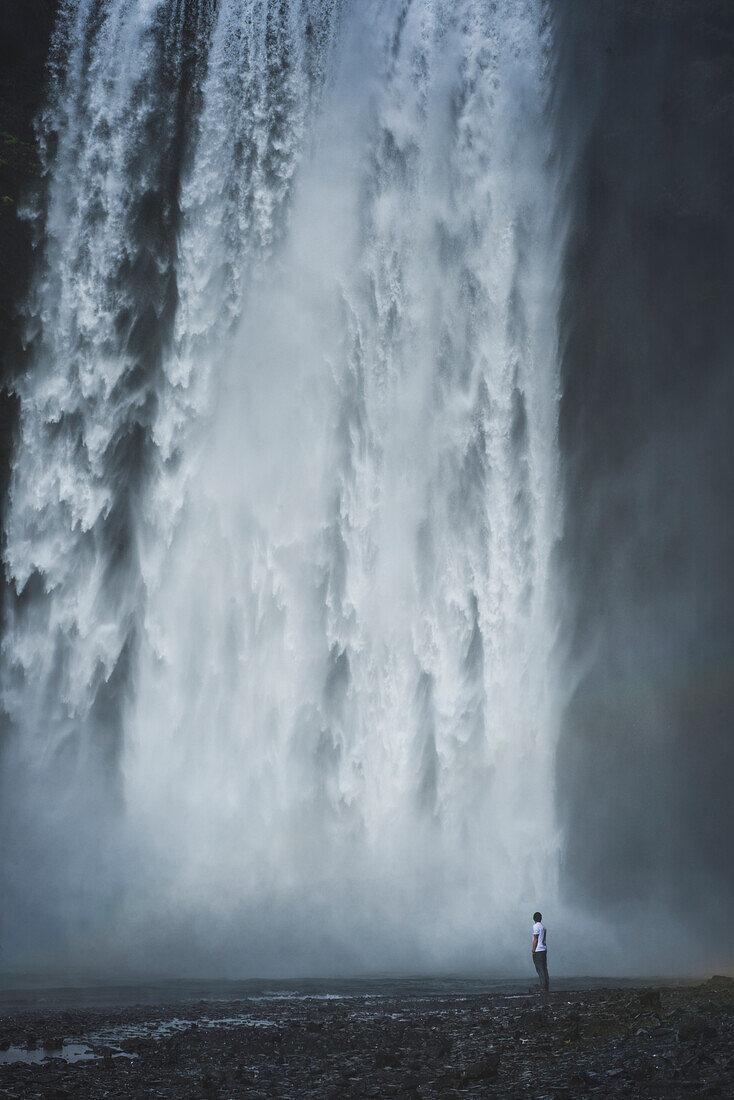 Mann, der am Skogafoss-Wasserfall in Island steht