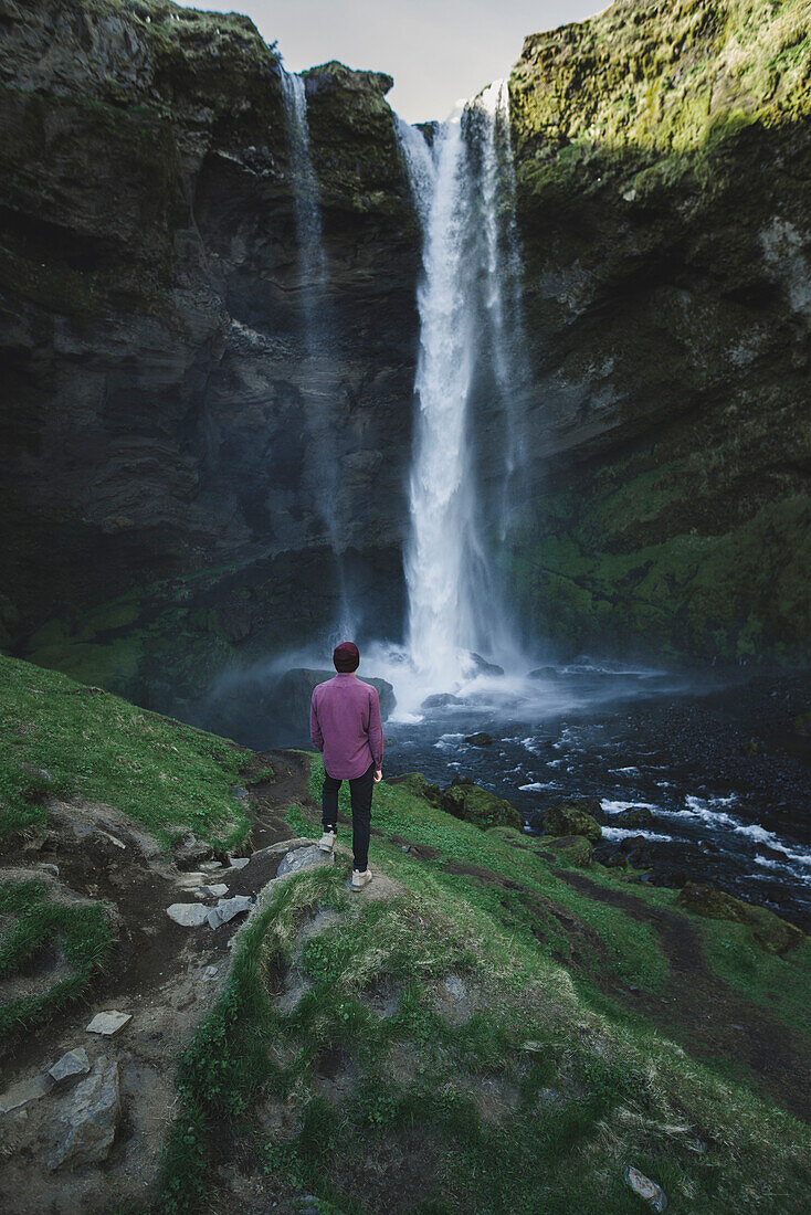 Mann, der am Kvernufoss-Wasserfall in Island steht