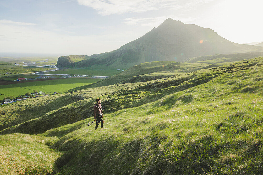 Mann spaziert auf einem Feld am Berg in Island
