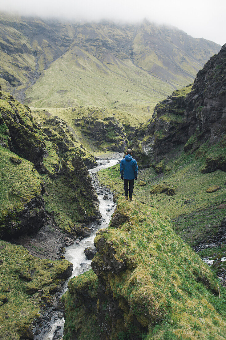 Mann, der durch den Talfluss in Island wandert